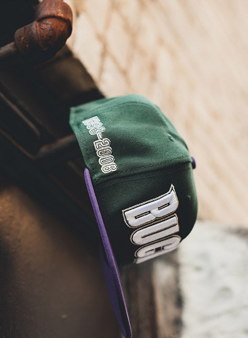 New Era 59Fifty HWC '93 Wordmark Milwaukee Bucks Fitted Hat In Green & Purple - Right Side View Lifestyle Photo On Ground