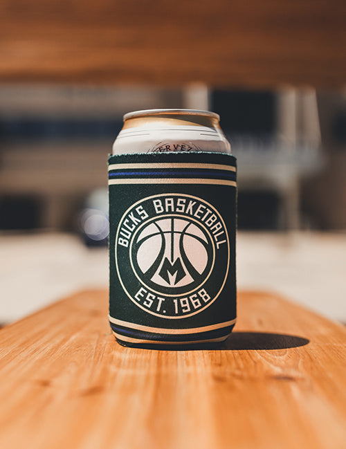 Logo Brand Establish Stripes Milwaukee Bucks Can Koozie In Green - Lifestyle Shot Of Koozie Standing On Bench With Can Inside