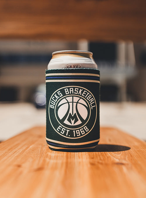 Logo Brand Establish Stripes Milwaukee Bucks Can Koozie In Green - Lifestyle Shot Of Koozie Standing On Bench With Can Inside